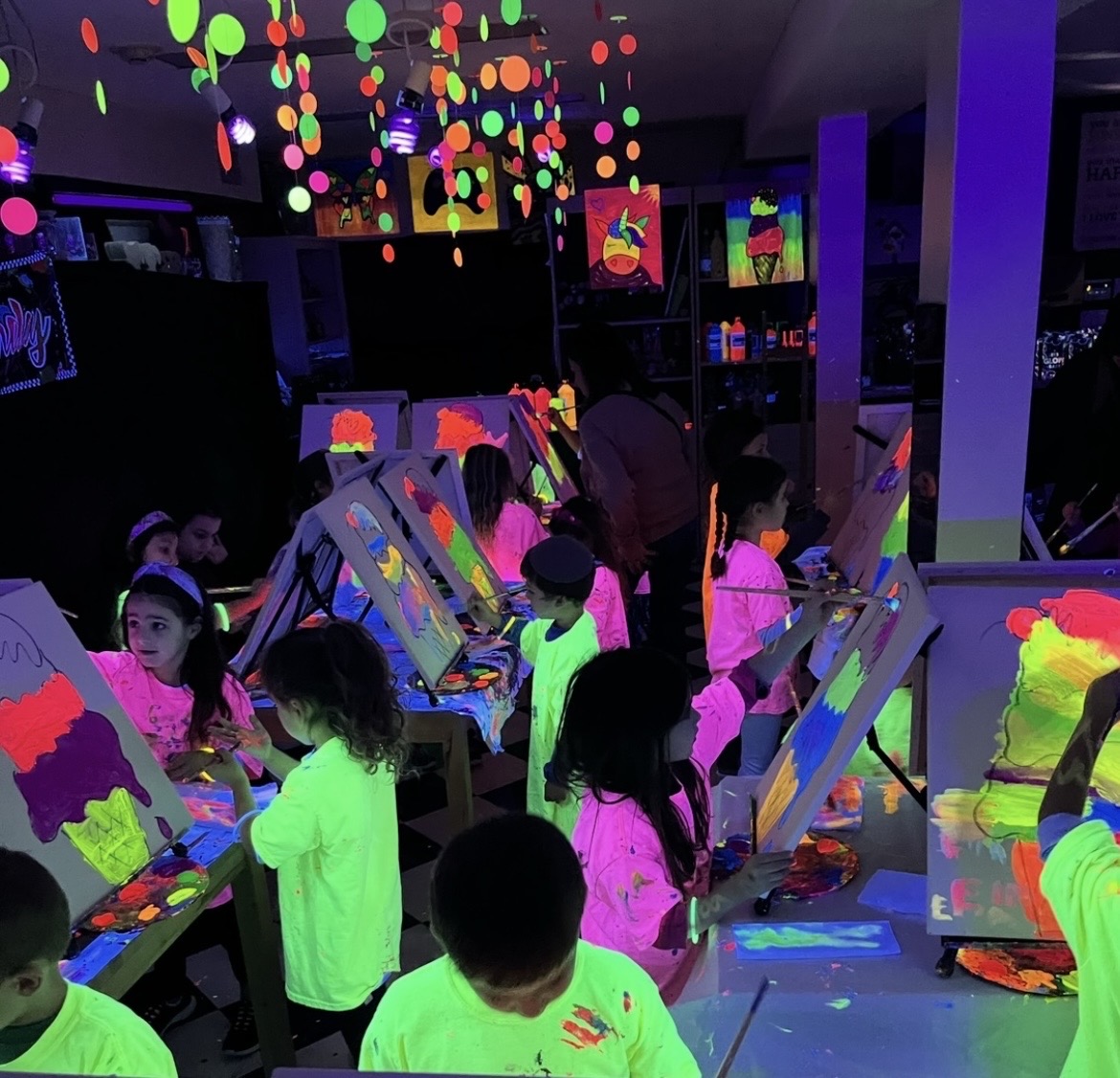 Children painting at Sunshine Pottery glow-in-the-dark party